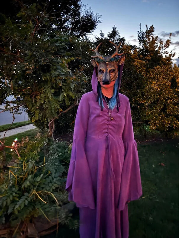 A person in a purple robe and deer mask standing outside as a cool Halloween costume idea.