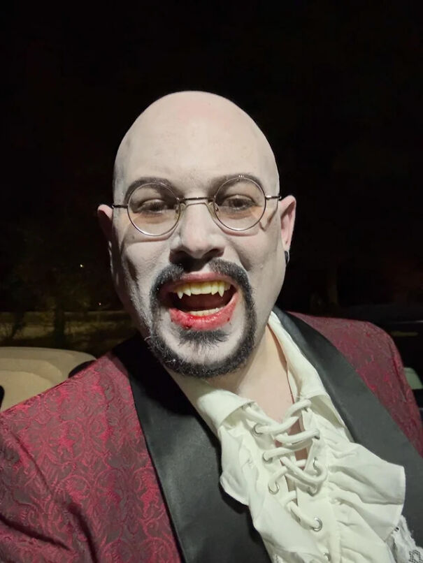 A man wearing vampire fangs and pale makeup as a cool Halloween costume idea.