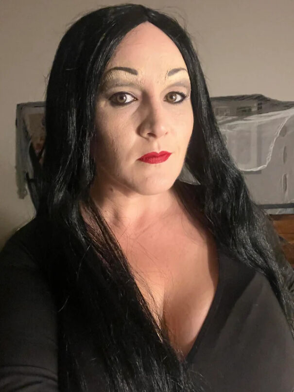 A woman with long black hair and dark makeup dressed as Morticia Addams for Halloween costume ideas.