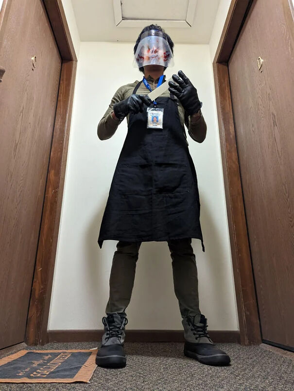 A person dressed as Dexter with a face shield and apron for a spooky Halloween costume.