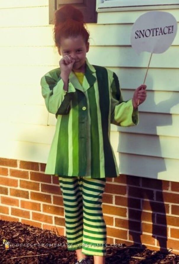 Young girl in a green striped outfit holding a speech bubble sign, showing unique Halloween costume ideas.