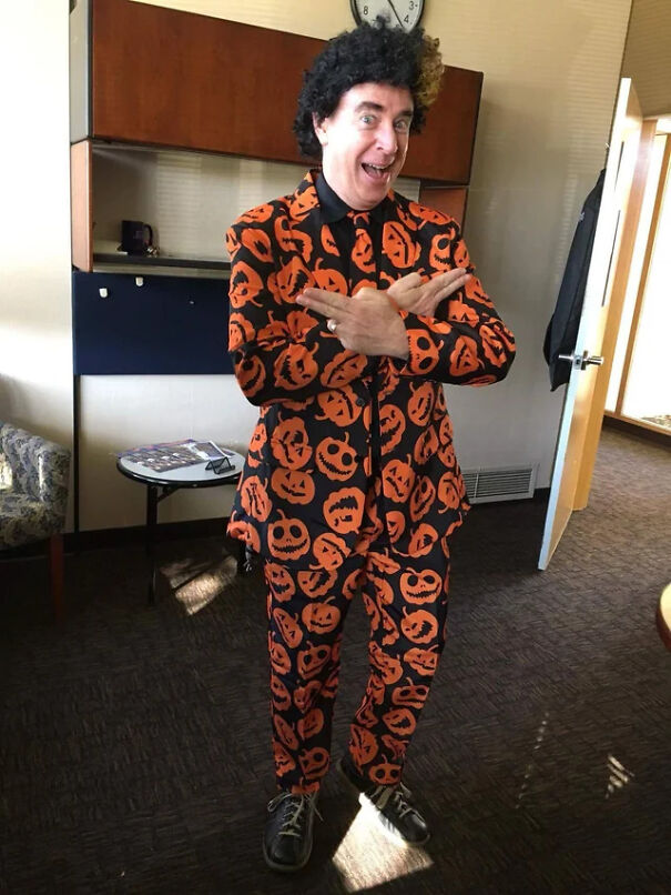 Man wearing a pumpkin patterned suit and wig, demonstrating creative Halloween costume ideas.