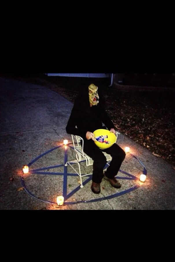 Person in a creature mask sitting inside a lit pentagram with candy bowl as a Halloween costume idea