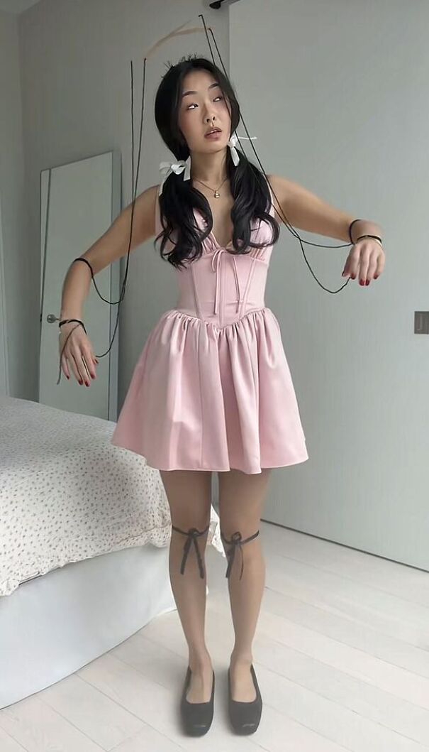 A woman dressed up as a marionette puppet in a pink dress for creative Halloween costume ideas.