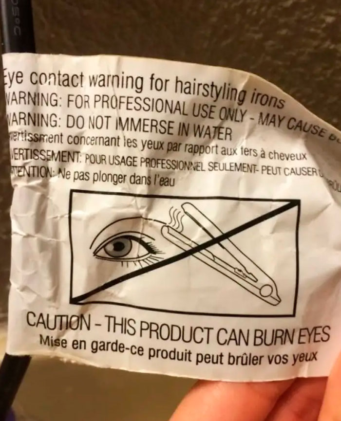 Warning tag on a hair straightener showing confusing labels and instructions against placing it near an eye.