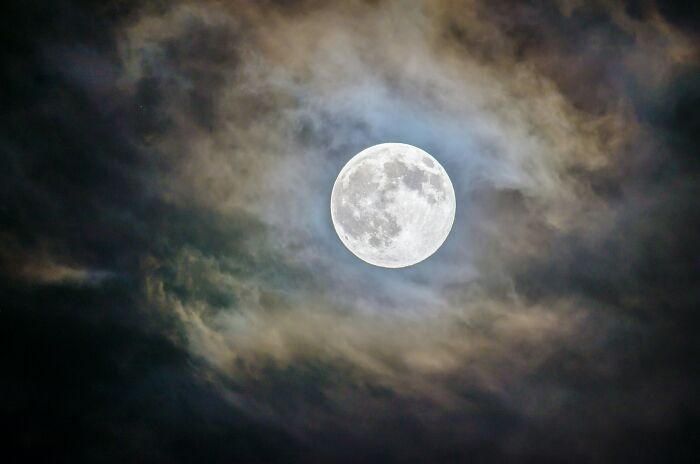 A bright full moon surrounded by dark clouds, a metaphor for partners questioning intelligence