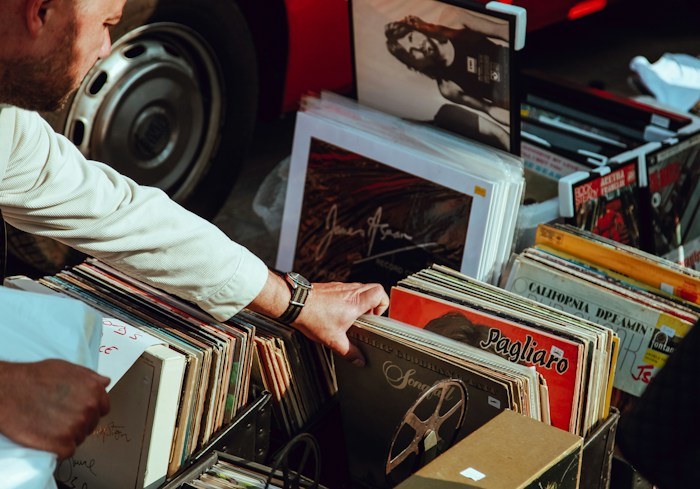 Person searching through vintage vinyl records, showcasing amazing dumpster finds.
