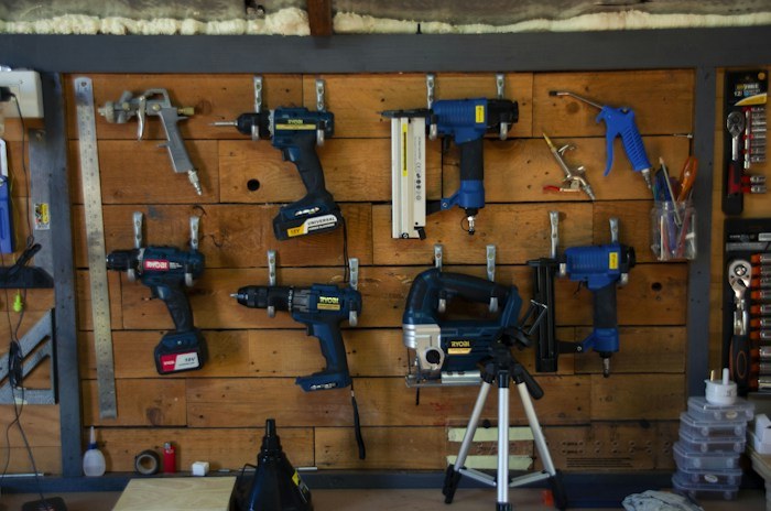 Power tools neatly mounted on a wooden pegboard wall, illustrating valuable dumpster finds.
