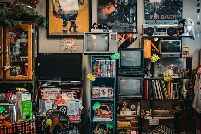 A room packed with vintage televisions, books, and memorabilia, exemplifying incredible dumpster finds.