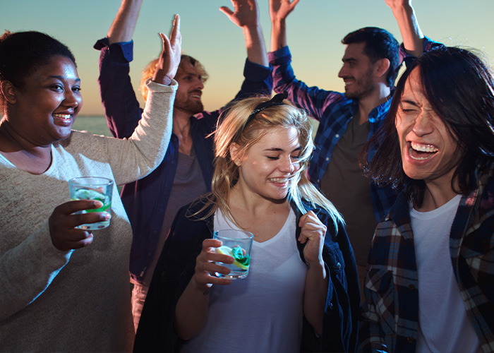 Group of friends partying together representing social expectations around hosting guests Group of friends partying together representing social expectations around hosting guests