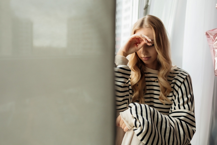 Upset woman sitting by window reflecting on SIL wedding drama and choosing an Australia trip. Upset woman sitting by window reflecting on SIL wedding drama and choosing an Australia trip.