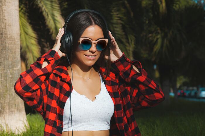 A young woman outdoors wearing headphones, coping with the impact of narcissistic parents.