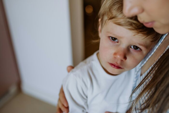 A sad young boy leaning closely against his mother during emotional times linked to petty family feuds