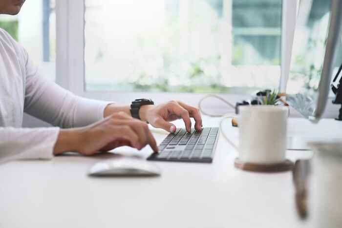 Close-up of a person typing on a keyboard at a desk, representing corporate industry insiders.