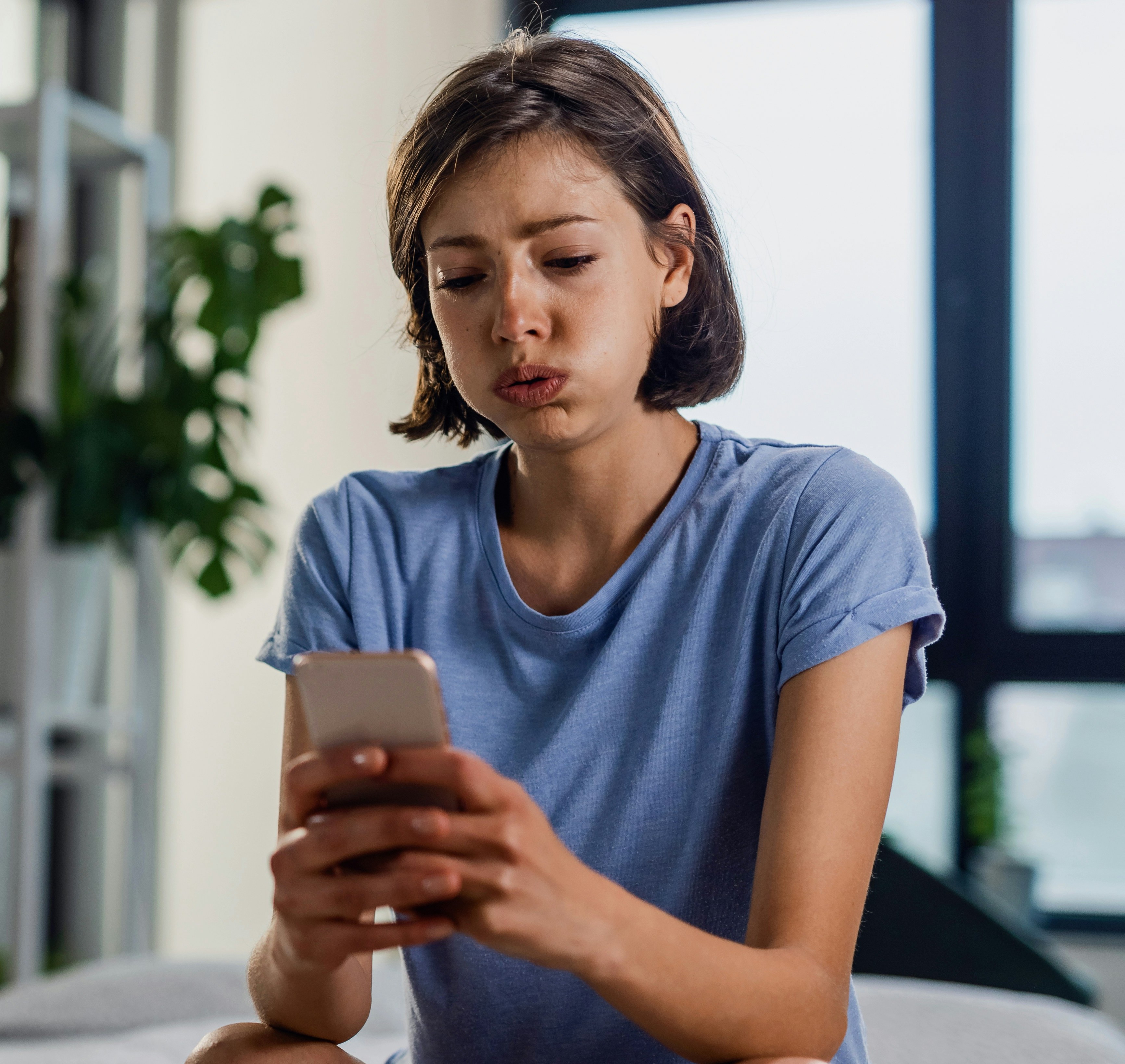 Upset woman looking at her phone as her friend group decides to go on a trip