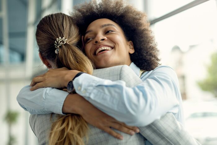 Two women sharing a warm hug, representing supportive behaviors and friendship in public