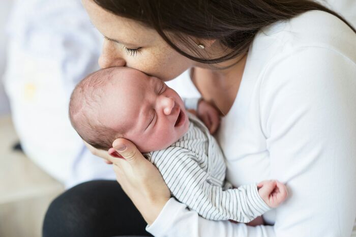 A mother kissing her newborn baby, representing situations where professionals said or did questionable things.