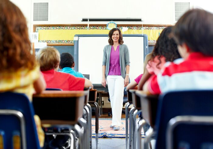 A teacher standing at the front of a classroom filled with elementary students in a tiny community