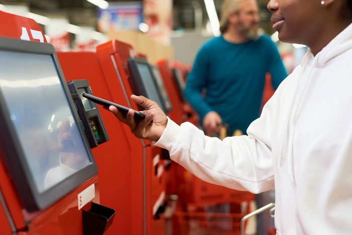 A close-up of a hand using a self-checkout machine, relating to when a woman accidentally forgets to pay at checkout A close-up of a hand using a self-checkout machine, relating to when a woman accidentally forgets to pay at checkout