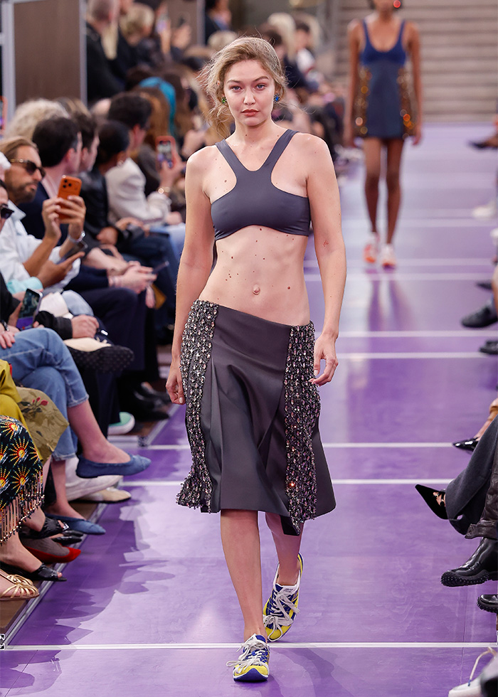 Gigi Hadid runway return in grey crop top and matching skirt on purple catwalk. Gigi Hadid runway return in grey crop top and matching skirt on purple catwalk.