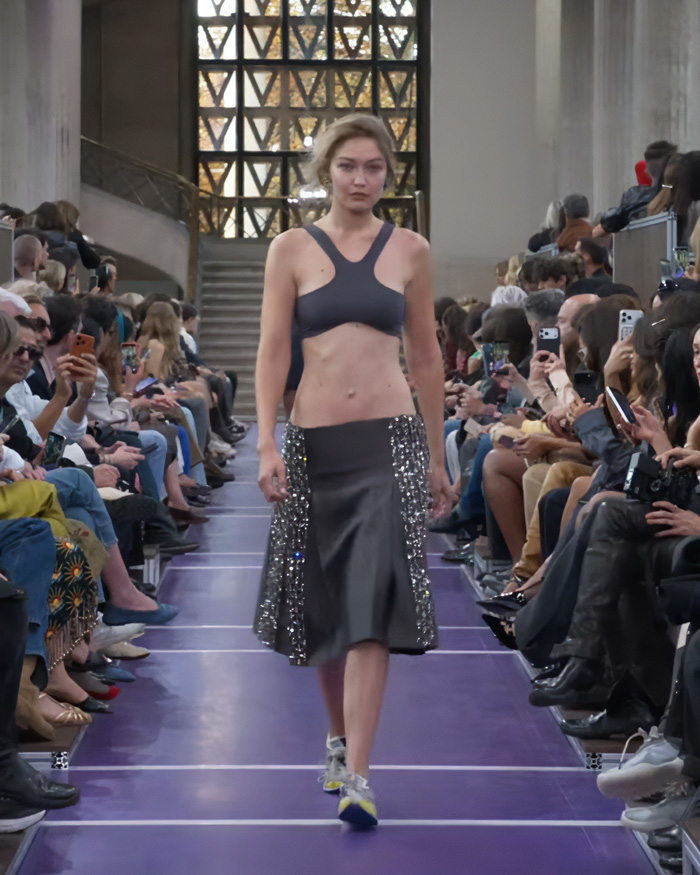 Gigi Hadid runway walk in grey skirt and top with spectators on both sides. Gigi Hadid runway walk in grey skirt and top with spectators on both sides.