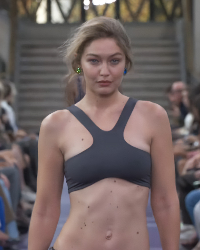 Close-up of Gigi Hadid runway walk wearing a dark grey athletic-style top. Close-up of Gigi Hadid runway walk wearing a dark grey athletic-style top.