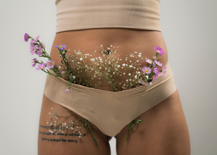 A woman wearing beige underwear filled with flowers, illustrating body naturalness A woman wearing beige underwear filled with flowers, illustrating body naturalness