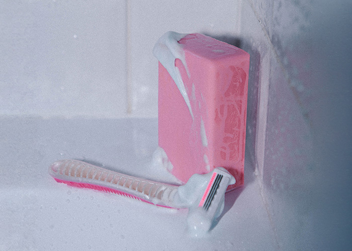 A pink razor and soap covered in foam, representing options to shave down there A pink razor and soap covered in foam, representing options to shave down there