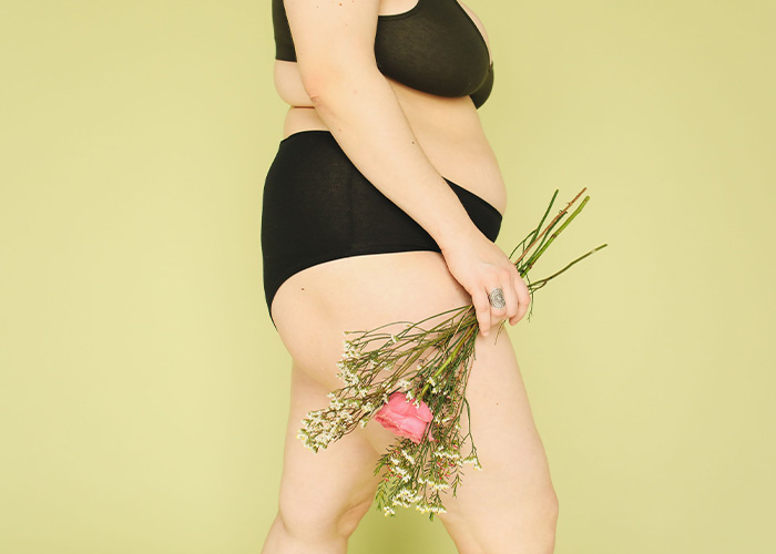 Woman holding flowers against a light background, discussing if you don’t shave down there. Woman holding flowers against a light background, discussing if you don’t shave down there.