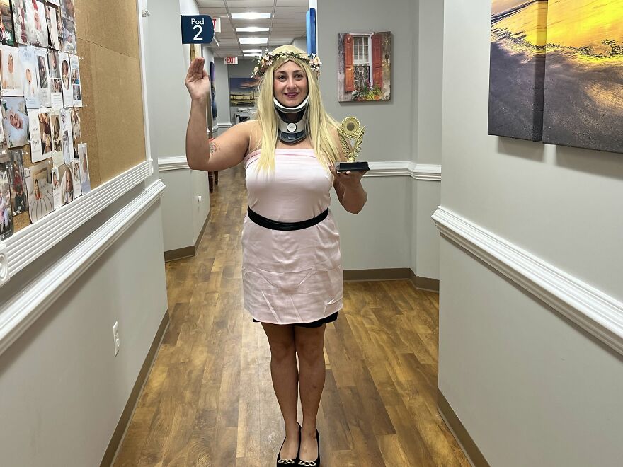 Woman wearing a neck brace and holding a trophy as a creative Halloween costume idea in an office.