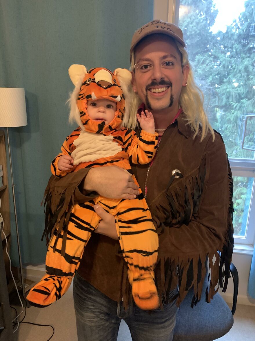 A man dressed as Joe Exotic holding a baby in a tiger suit, serving as creative Halloween costume ideas.
