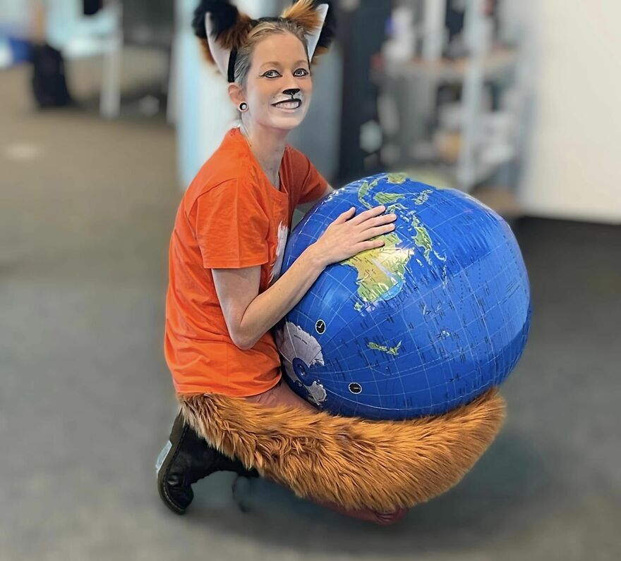 A woman dressed up as the Firefox browser logo holding a globe for creative Halloween costume ideas.