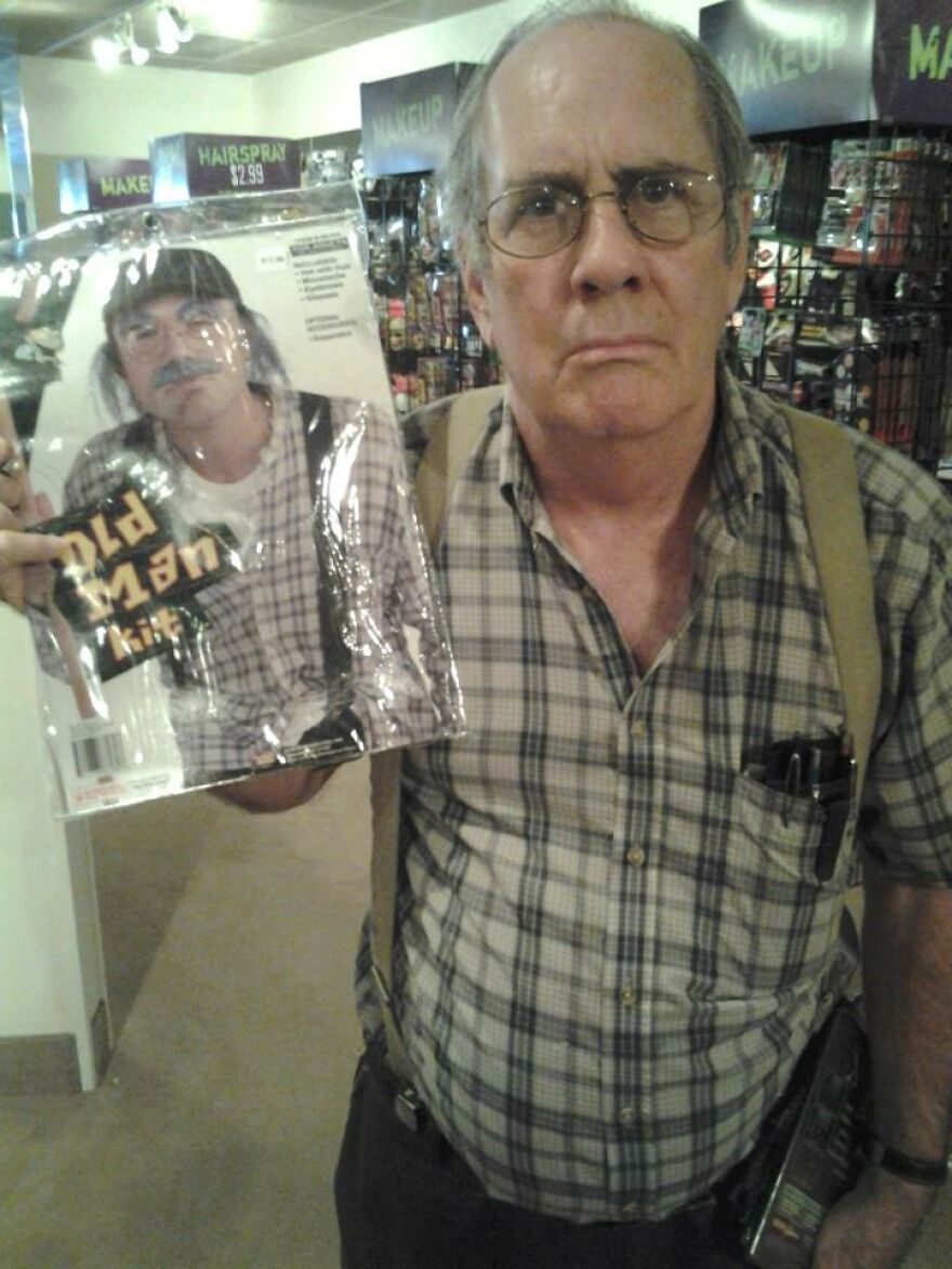 An older man holding an old man Halloween costume kit in a store