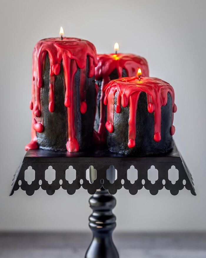 Tall black pillar candle cakes dripping with red frosting icing featured as spooky Halloween foods.