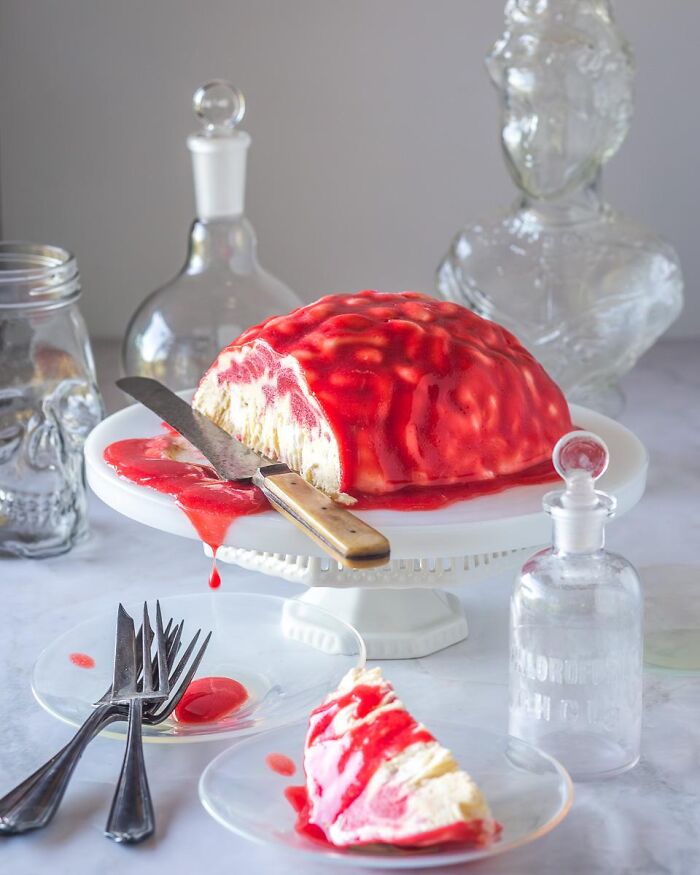 A realistic brain cake served with red berry sauce as creative Halloween foods for a party dessert display.