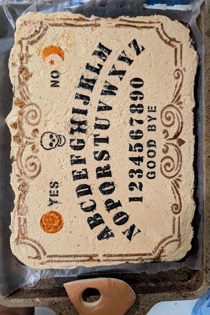 Sheet cake decorated like a Ouija board with icing letters, perfect for Halloween foods.