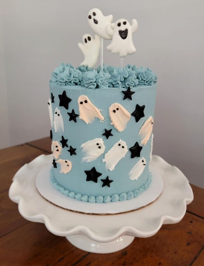 A light blue cake decorated with white ghost frosting patterns as part of festive Halloween foods.