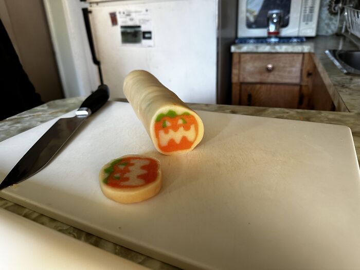 A slice of pumpkin roll cookie dough on a cutting board representing fun Halloween foods ideas.
