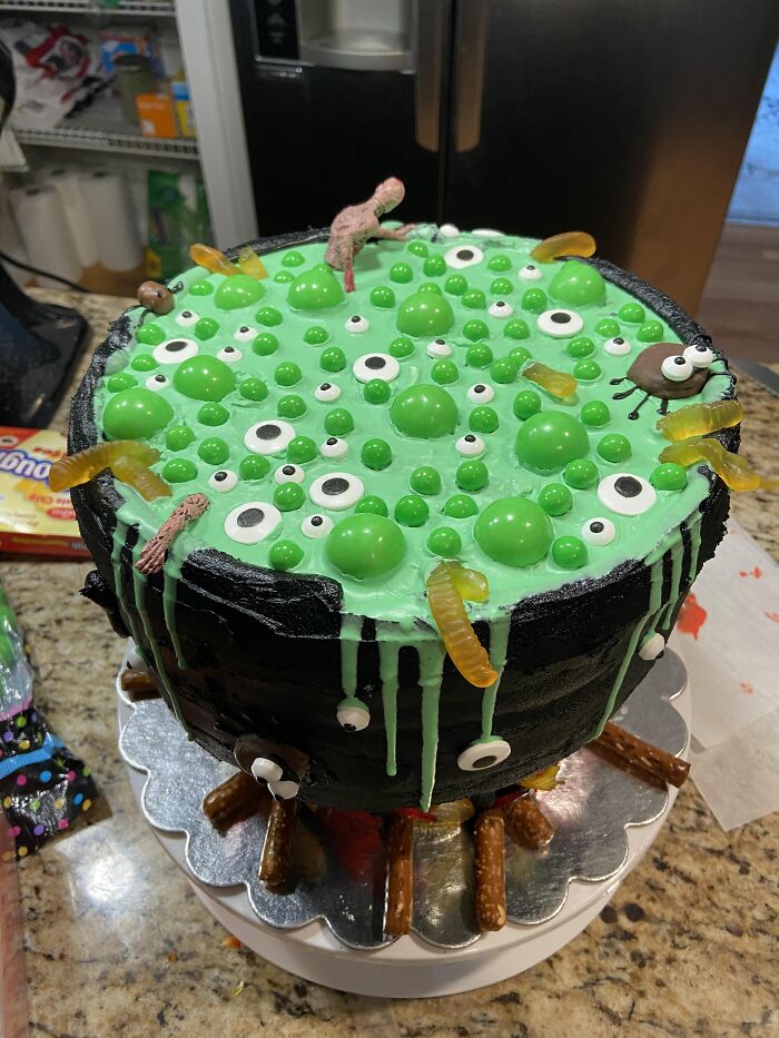 Witches cauldron cake topped with green slime and eyeballs as creative Halloween foods