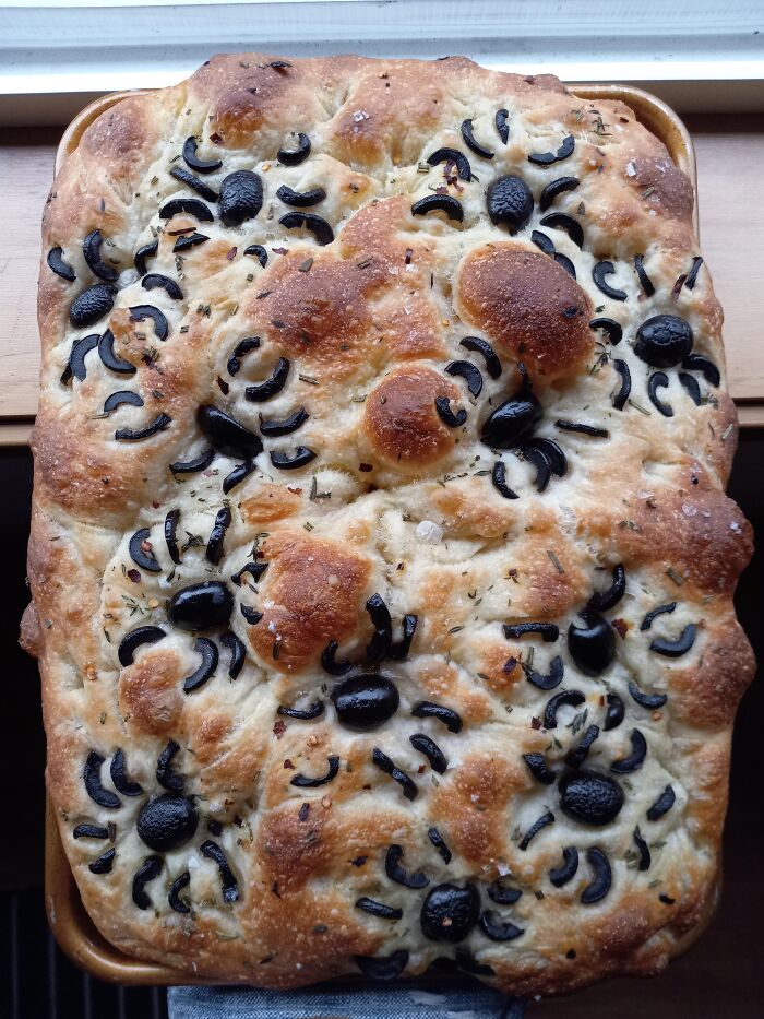 Freshly baked focaccia bread designed as Halloween foods featuring black olive spiders