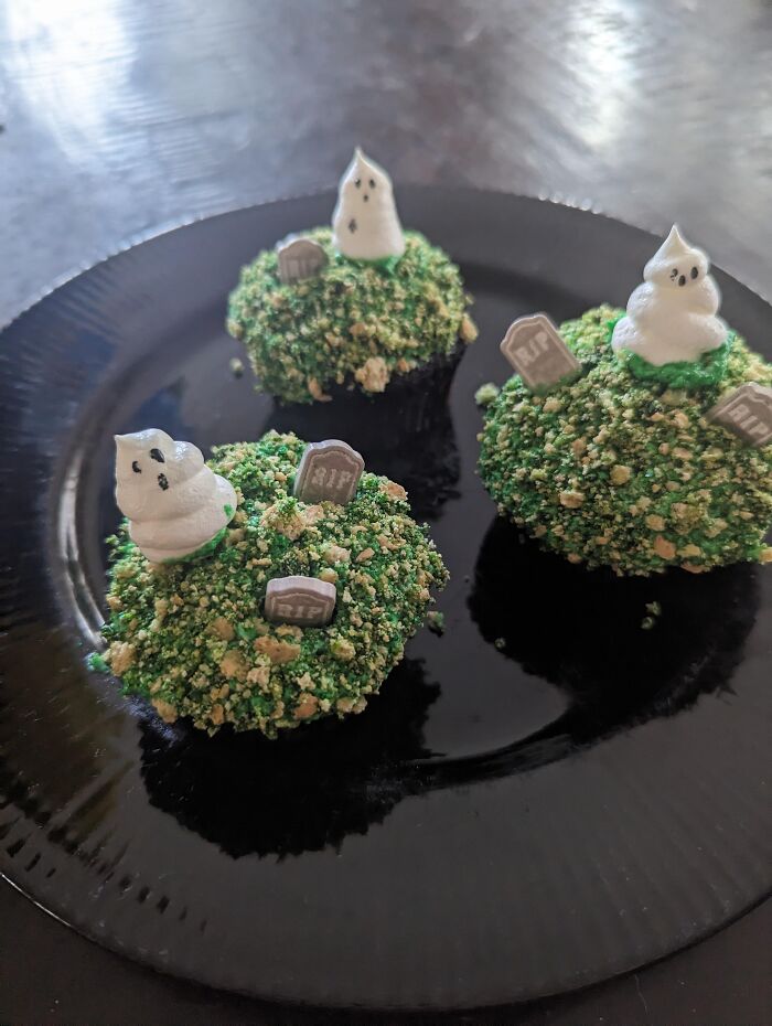 Graveyard themed Halloween foods with meringue ghosts and tombstone decorations on green frosting