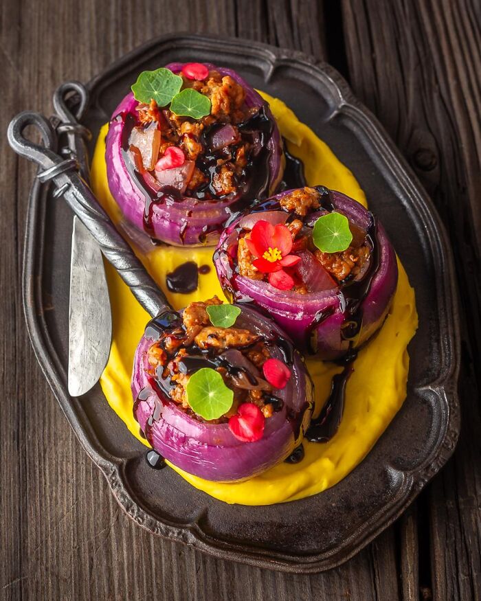 Stuffed red onions plated with yellow puree, serving as creative Halloween foods.