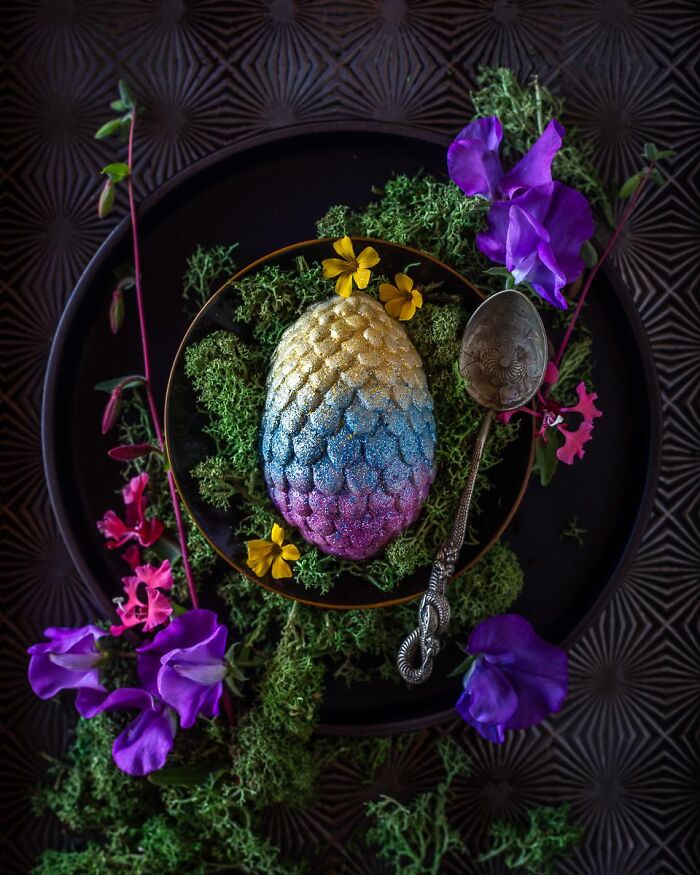 Glittery dragon egg dessert surrounded by purple flowers as magical Halloween foods.