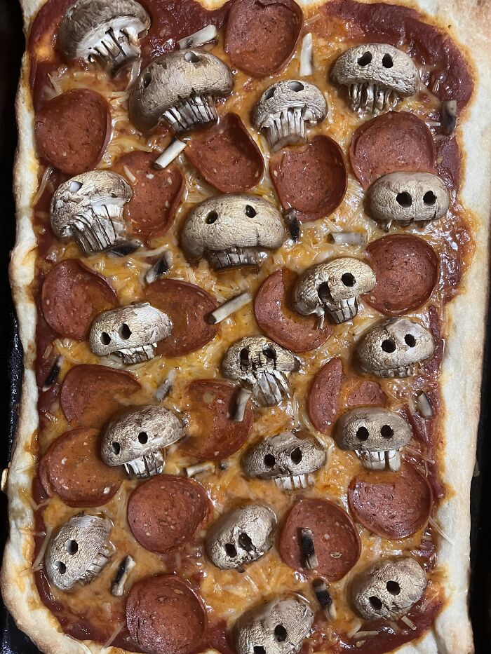 Pepperoni pizza topped with skull-carved mushrooms as spooky Halloween foods.