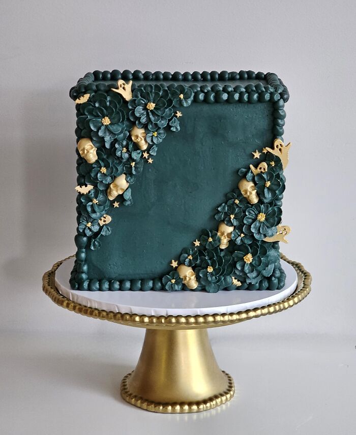 Dark green square cake decorated with golden skulls and buttercream flowers for Halloween foods