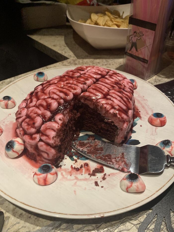 Realistic brain cake served on a plate surrounded by candy eyeballs as creative Halloween foods