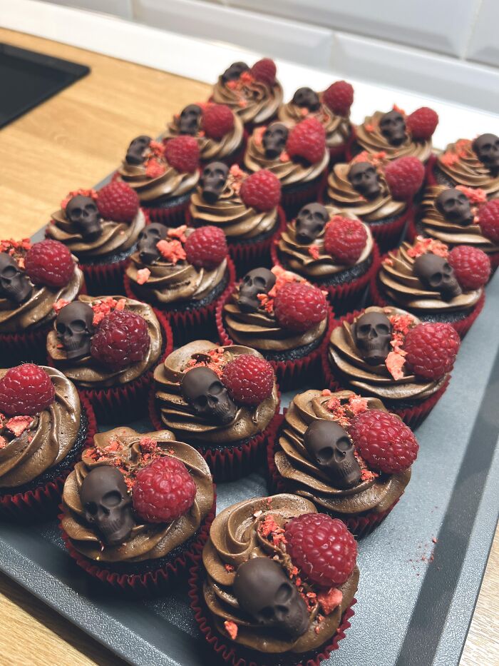 Chocolate cupcakes topped with fresh raspberries and mini skulls for creative Halloween foods