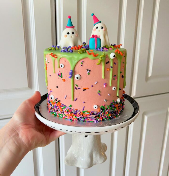 Colorful pink celebration cake with ghost toppers as fun Halloween foods.