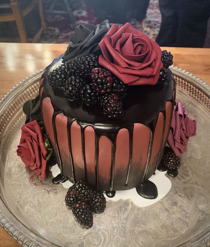 Gothic dark chocolate drip cake styled as creepy Halloween foods with red roses and blackberries