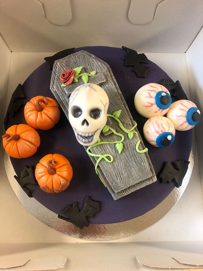 Spooky Halloween cake decorated with fondant skull, coffin, eyeballs, and pumpkins